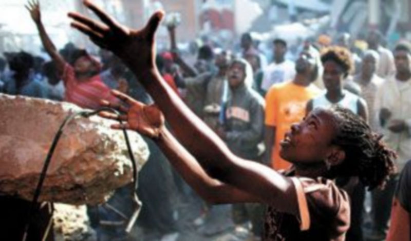 Una joven intenta conseguir alguno de los bienes que arrojan los saqueadores de un comercio de Puerto Príncipe destruido por el terremoto. / REUTERS