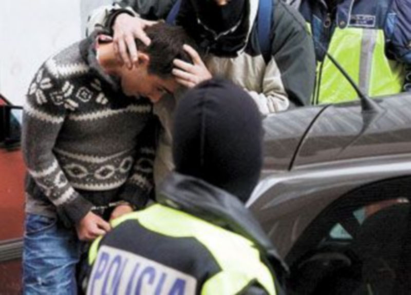 Varios agentes de la Policía encapuchados introducen en un automóvil a uno de los terroristas capturados el fin de semana. / EFE