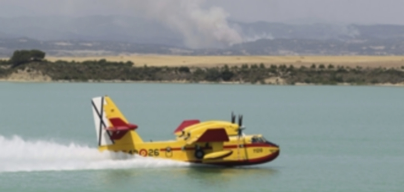 Un hidroavión Canadair CL-415 carga agua en el embalse de Laverne para combatir el incendio que consume bosques y cultivos de la provincia de Zaragoza. / Efe