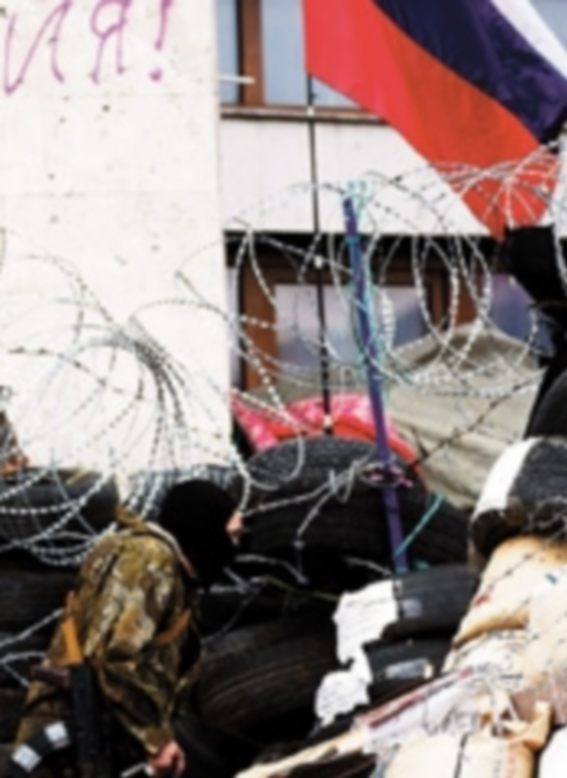 Un miliciano vigila una barricada levantada ante un edificio público. / Reuters