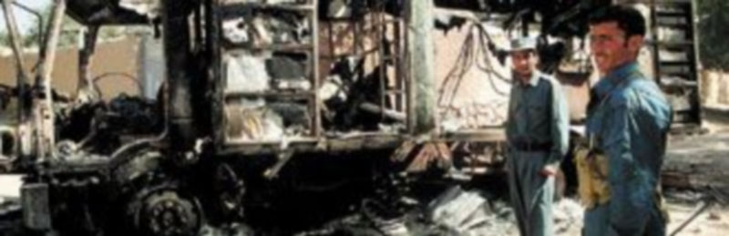 Dos policías afganos hacen guardia junto a un camión quemado por un grupo de insurgentes