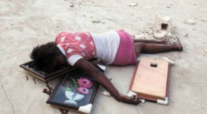 Una joven yace muerta tras ser disparada en la cabeza cuando recogía objetos entre las ruinas de Puerto Príncipe. / REUTERS