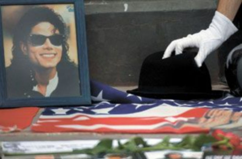 Un admirador de Michael Jackson deposita un sombrero junto a su foto durante un homenaje. / EFE