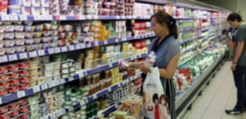 Una mujer observa con detenimiento varios artículos en la sección de lácteos de un supermercado moscovita