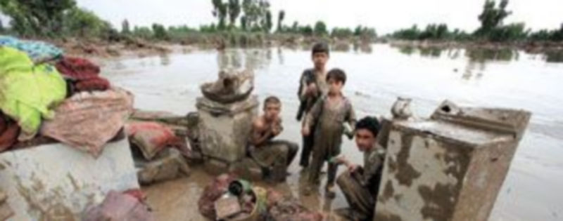 Varios niños permanecen sentados entre sus pertenencias en una zona inundada de la provincia paquistaní de Khyber-Pakhtunkhwa. / Reuters