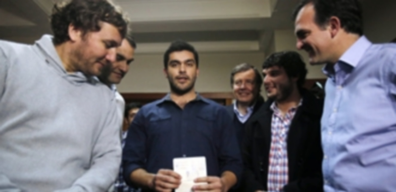 Felipe Cuevas muestra su pasaporte durante una rueda de prensa a la que acudió rodeado de compañeros. / efe