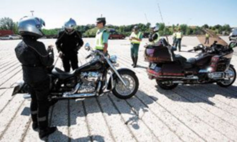 Agentes de la Guardia Civil comprueban si los cascos de dos motoristas están homologados. / EFE