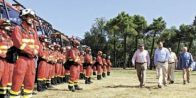 Alejo y Silván pasan junto a algunos de los profesionales que operan en la base contra incendios de Tabuyo del Monte. / Ical