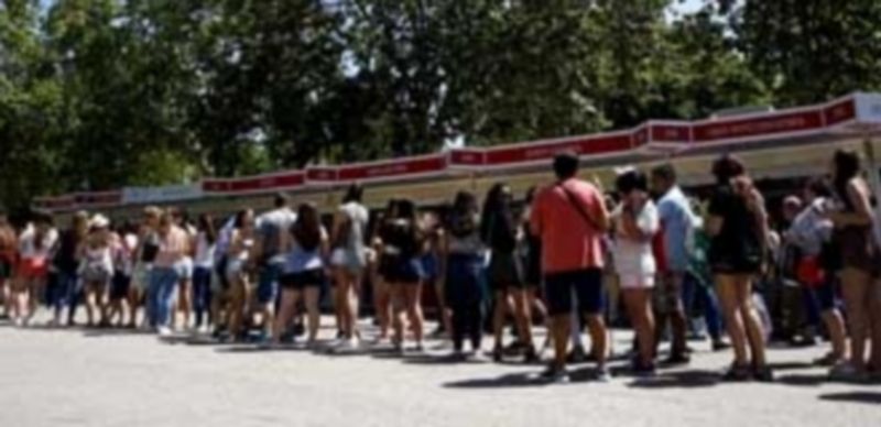 Varios jóvenes se agolpan en las casetas de la Feria del Libro de Madrid para intentar conseguir sus ejemplares favoritos. / Efe