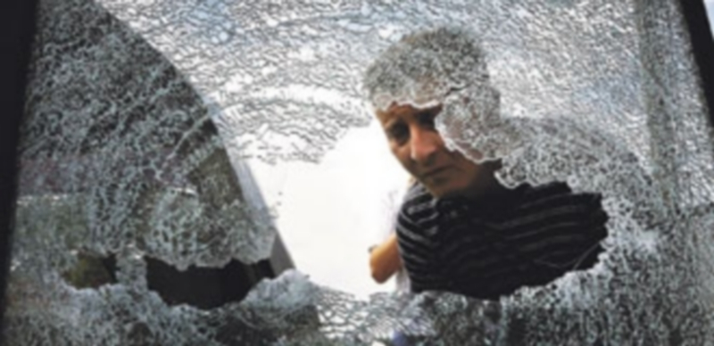 Un vecino de Lugansk contempla un cristal roto tras los combates entre militares gubernamentales y separatistas prorrusos. / Reuters