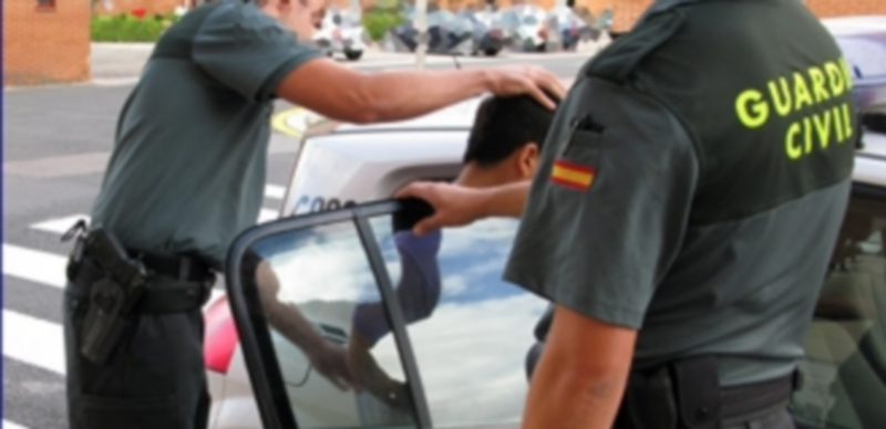 Dos agentes de la Guardia Civil introducen en un vehículo del cuerpo a un detenido