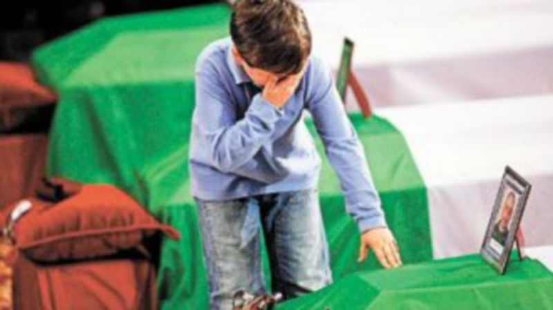 El hijo de uno de los soldados italianos muertos en Kabul el pasado jueves toca el féretro de su padre durante el funeral que se ofició ayer en Roma. /EFE