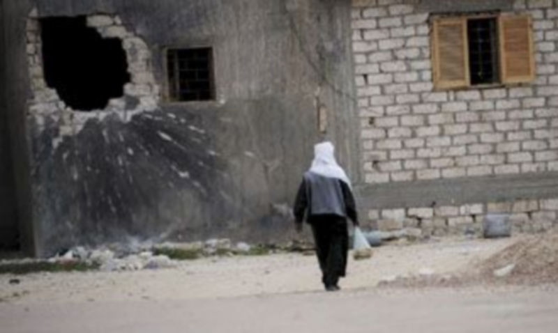 Un ciudadano camina cerca de un edificio dañado por un misil en la localidad de Ajdabiya. / Efe