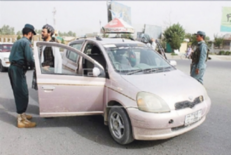 Varios oficiales de seguridad afganos cachean a algunas personas en la ciudad de Kandahar