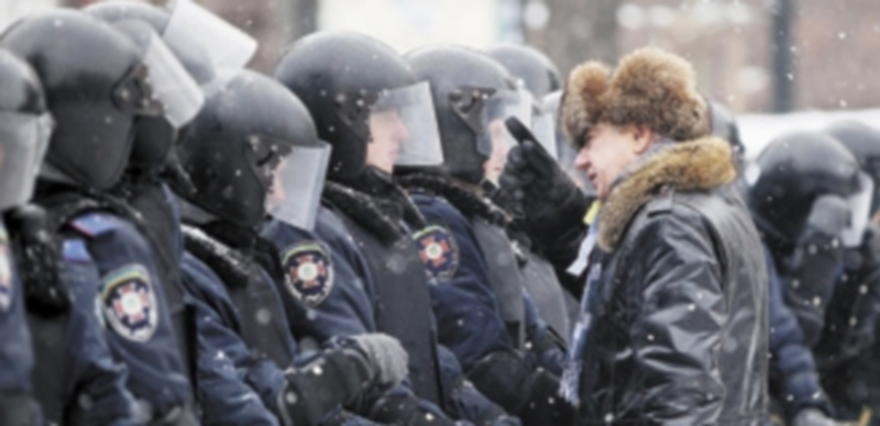 Un ciudadano se acerca a conversar con los agentes del Orden en las calles de Kiev. / Efe