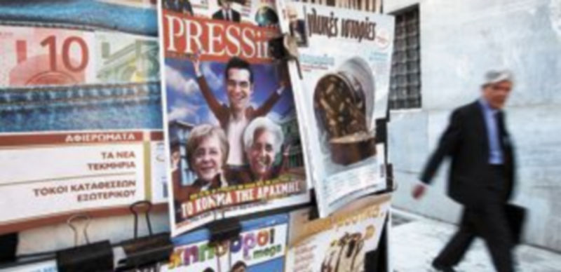 Un ciudadano griego pasea por una calle de Atenas junto a las portadas de los principales periódicos. / Reuters
