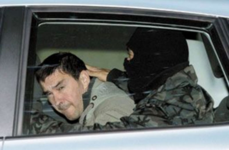 Un agente de las Fuerzas de Seguridad del Estado con la cabeza cubierta con un pasamontañas fue el encargado de escoltar a Otegi hasta la sede de la Audiencia . /EFE