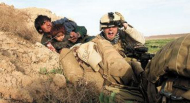 Un ‘marine’ estadounidense protege a un afgano y a su hijo de los disparos de los talibanes en las afueras de la ciudad de Marjah. / Reuters