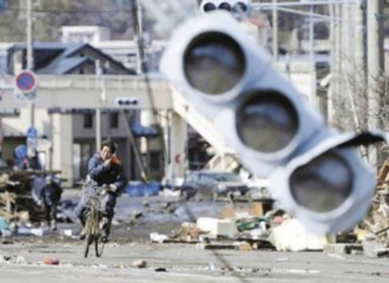 Un japonés transita en bicicleta entre los escombros por una calle de la ciudad de Miyako