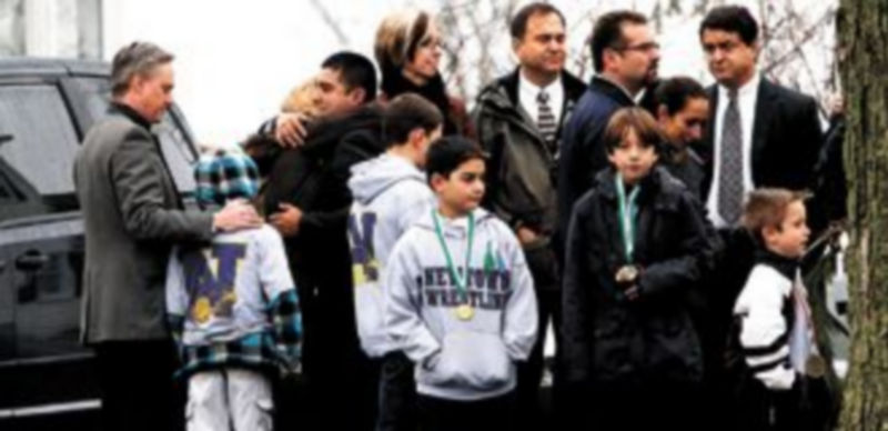 Varios compañeros del equipo de lucha de uno de los fallecidos acuden al funeral con sus padres. / Reuters