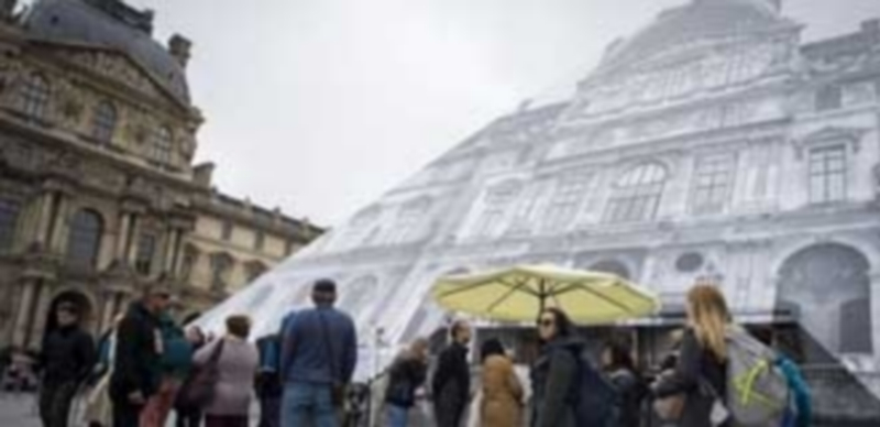 Un grupo de turistas en París observa los carteles que informan de que el Museo del Louvre permanece cerrado. / Efe