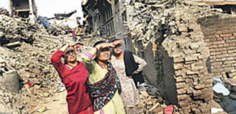 Tres mujeres observan las labores de desescombro en una zona devastada a las afueras del valle de Katmandú. / Efe