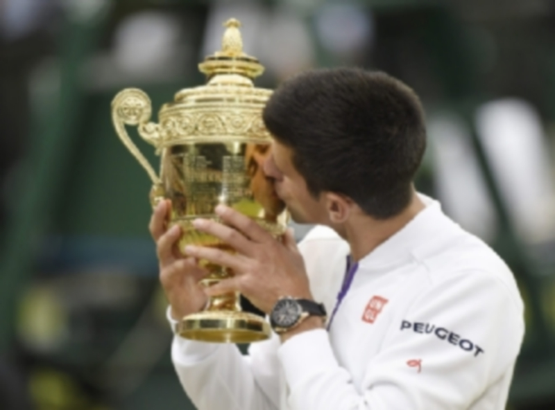 Novak Djokovic besa el trofeo como vencedor en el All England Tennis Club. / EFE