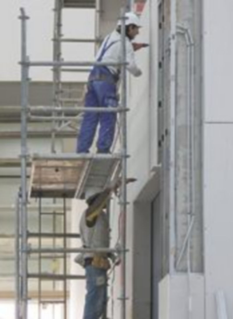 Dos trabajadores retocan la fachada de un edificio. / Jesús Matías