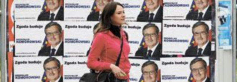 Una joven polaca pasea por el centro de Varsovia junto a unos carteles con el candidato presidencial Bronislaw Komorowski. / Reuters