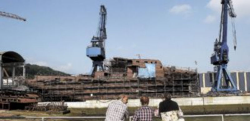 Tres personas observan un buque en construcción en el astillero de Pasaia (Guipúzcoa)