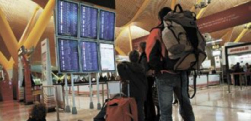 Imagen de archivo de un grupo de pasajeros comprobando en el panel informativo los vuelos cancelados de Iberia. / Reuters