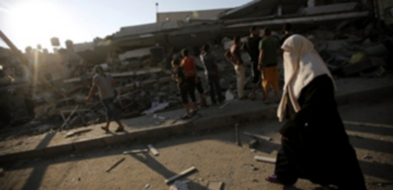 Unos palestinos observan un edificio destruido por proyectiles del Ejército israelí en la ciudad de Gaza. / Efe