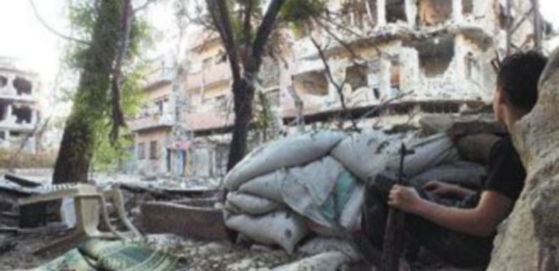 Un joven sirio observa desde una pequeña trinchera los bombardeos perpetrados en Homs