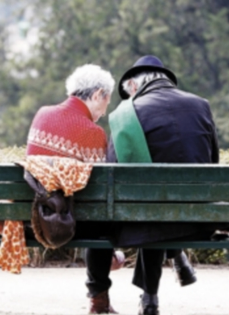 Una pareja de pensionistas cambia impresiones en un parque.