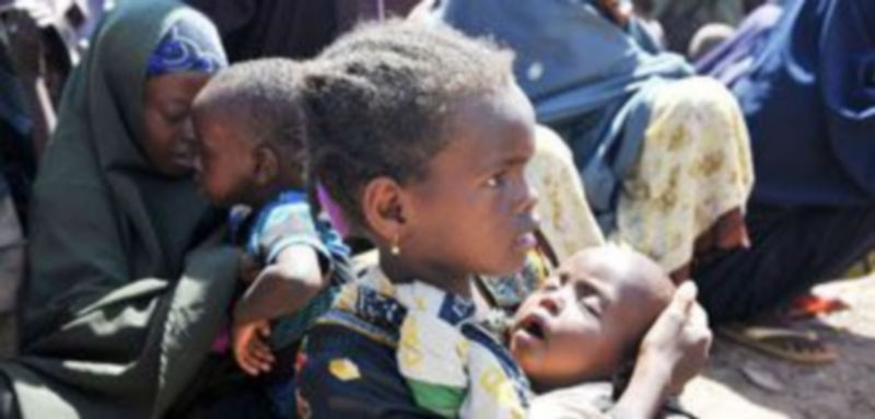 Una niña sostiene a su hermana pequeña mientras esperan la ayuda de una fundación humanitaria en Mogadiscio. / Efe