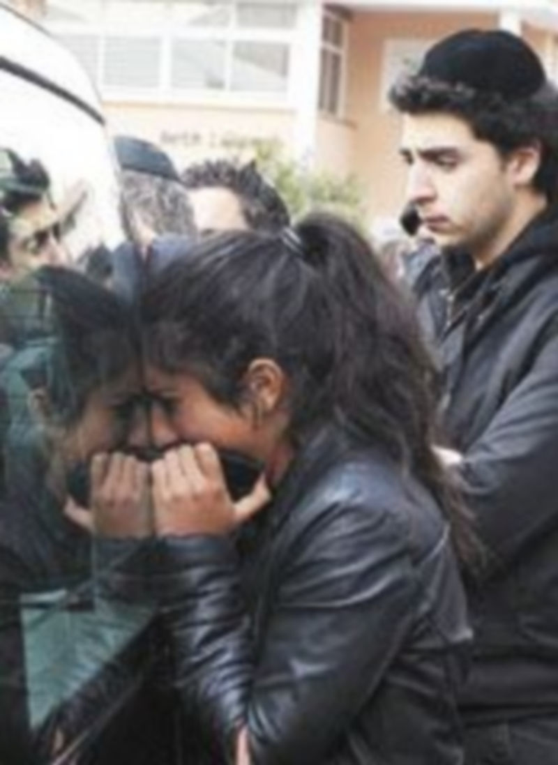 Una mujer llora sobre uno de los coches fúnebres. / Reuters