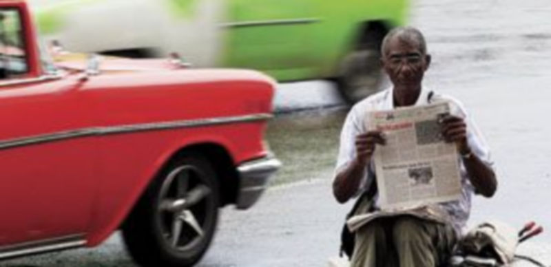 Un hombre lee en ‘Granma’ el texto que proclama la nueva normativa. / Reuters