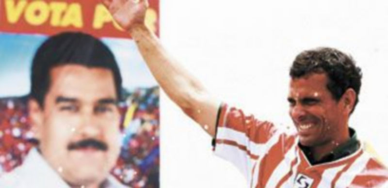 Henrique Capriles saluda a sus seguidores delante de un cartel de su adversario en los comicios del próximo domingo