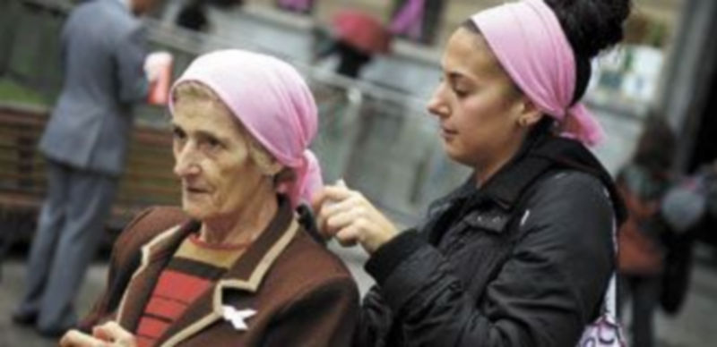 Una joven anuda un pañuelo rosa