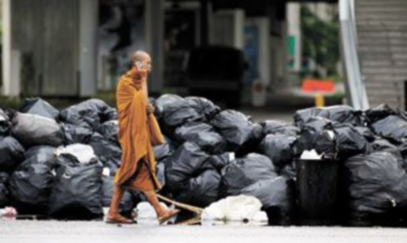 Un monje budista camina delante de una de las barricadas que limitan la zona ocupada por los opositores. /REUTERS