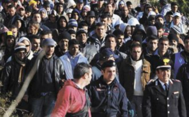 Varios agentes acompañan a decenas de inmigrantes indocumentados a su llegada a Lampedusa. / Efe.