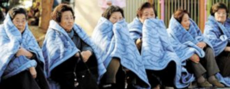 Todo Japón se paralizó ante el seísmo. Unas mujeres evacuadas de los edificios de trabajo reciben mantas y asistencia en la calle. / Reuters
