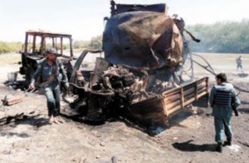 Varios policías inspeccionan uno de los camiones cisterna que resultaron calcinados por el bombardeo en Kunduz. / EFE