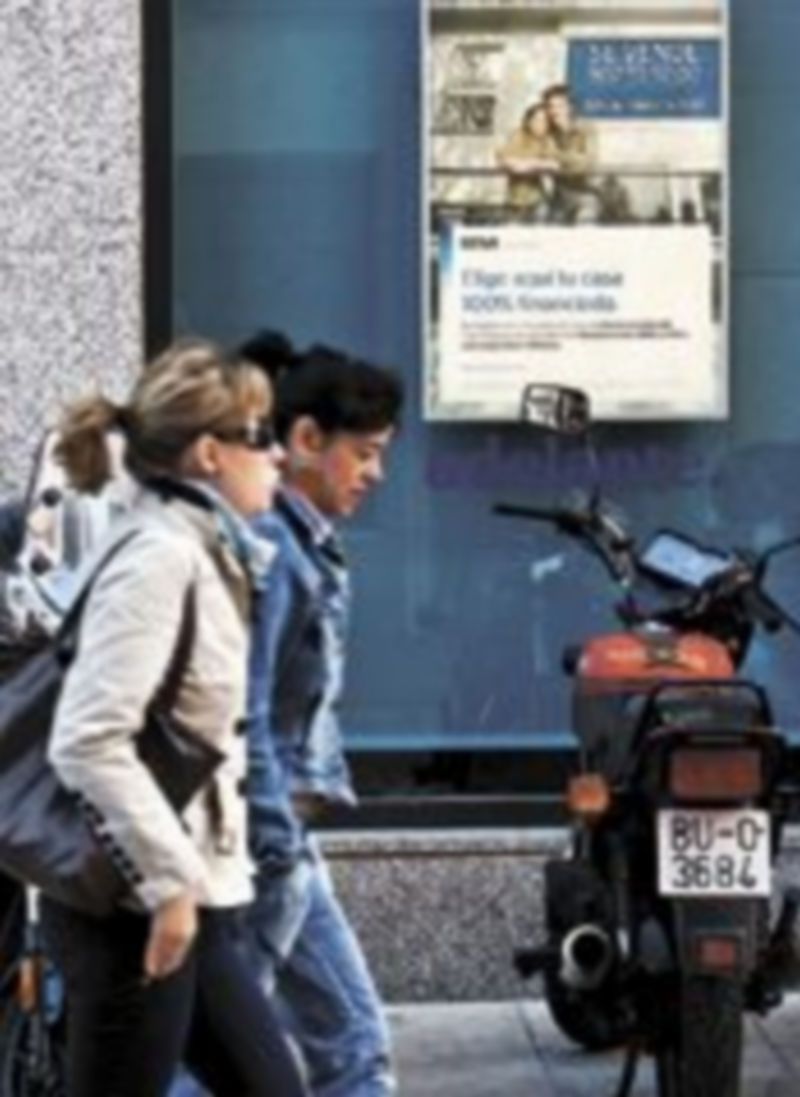 Dos jóvenes pasan delante de un anuncio sobre vivienda. / Luis López Araico