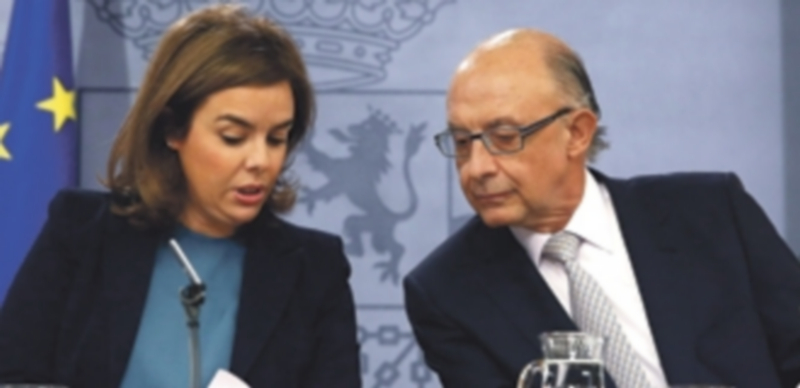 Cristóbal Montoro dialoga con Soraya Sáenz de Santamaría durante la rueda de prensa ofrecida el viernes. / Efe