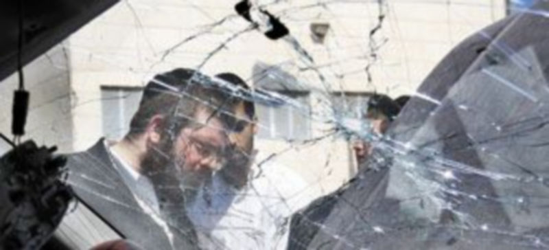 Dos israelíes miran los desperfectos ocasionados en su coche tras el cohete lanzado por las milicias palestinas. / Amir Cohen (Reuters)