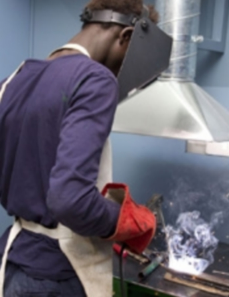 Un inmigrante africano trabaja el metal con una radial. / Ep.