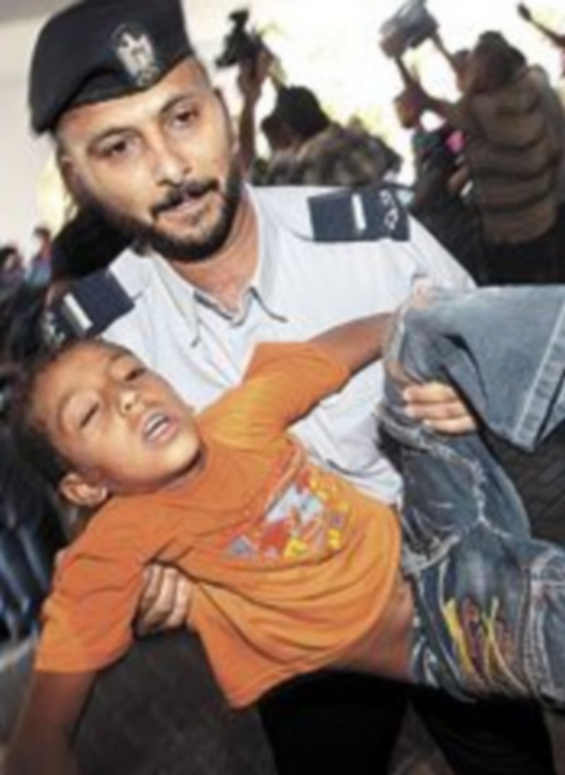 Un policía lleva en brazos a un herido.