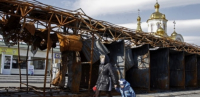 Una mujer pasea junto a un niño cerca de los restos de un mercado bombardeado en el centro de Donetsk