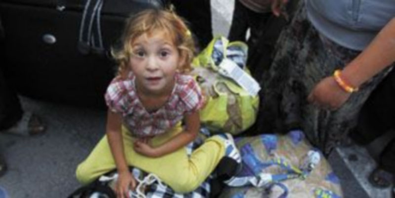 Una niña gitana observa a la cámara mientras ella y su familia preparan las maletas para abandonar un campamento desmantelado por el Gobierno francés. / Efe